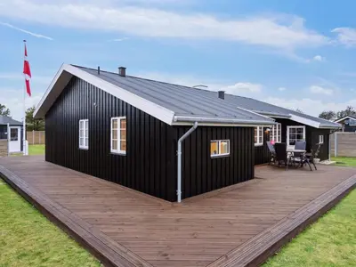 a black house with a wooden deck at Holiday Home Svante - 600m from the sea by Interhome in Blokhus