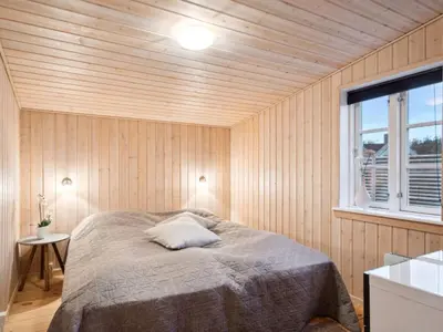 a bedroom with a bed in a wooden wall at Holiday Home Svante - 600m from the sea by Interhome in Blokhus