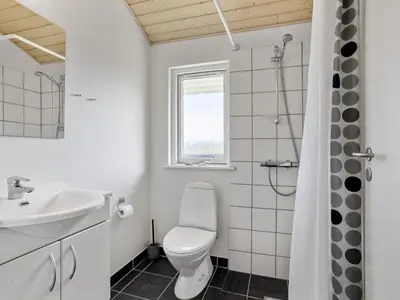 a white bathroom with a toilet and a sink at Holiday Home Joris - 1-5km from the sea by Interhome in Løkken