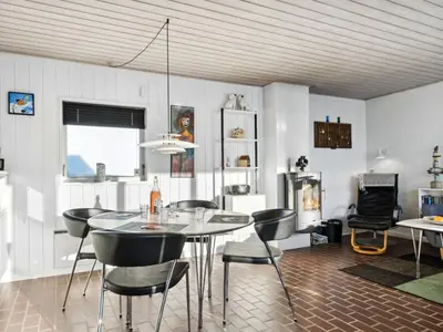 a dining room with a table and chairs and a fireplace at Holiday Home Leny - 900m from the sea by Interhome in Pandrup