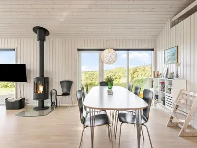 a dining room with a table and chairs and a fireplace at Holiday Home Mirla - 50m from the sea by Interhome in Saltum
