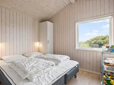 a bedroom with a bed in a room with a window at Holiday Home Mirla - 50m from the sea by Interhome in Saltum