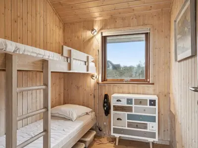 a bedroom with bunk beds in a wooden cabin at Holiday Home Gidske - 300m from the sea by Interhome in Blokhus