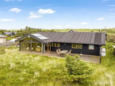 a black house in a field with grass at Holiday Home Gidske - 300m from the sea by Interhome in Blokhus