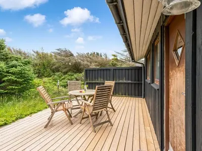 a wooden deck with a table and chairs on it at Holiday Home Gidske - 300m from the sea by Interhome in Blokhus
