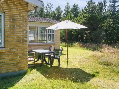 a table and chairs under an umbrella in a yard at Holiday Home Gisa - 400m from the sea by Interhome in Fjerritslev