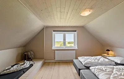a attic room with two beds and a window at Nice Home In Thyholm With Wifi in Thyholm