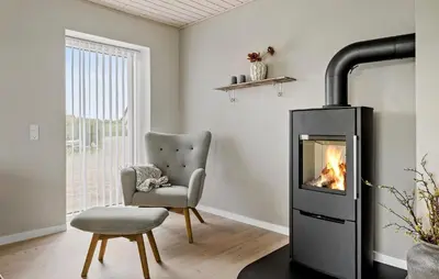 a living room with a fireplace and a chair at Nice Home In Thyholm With Wifi in Thyholm