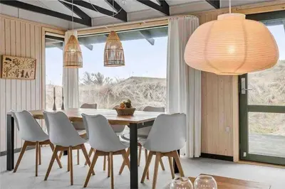 a dining room with a table and white chairs at Veludstyret sommerhus i unik natur 350 m fra lækker badestrand - helårsbolig in Saltum