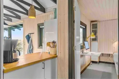a kitchen in a tiny house with a counter and a sink at Veludstyret sommerhus i unik natur 350 m fra lækker badestrand - helårsbolig in Saltum