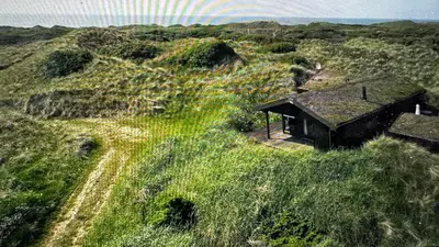 a small house on top of a grassy hill at Veludstyret sommerhus i unik natur 350 m fra lækker badestrand - helårsbolig in Saltum