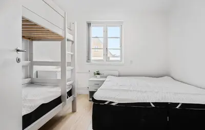 a white bedroom with a bunk bed and a window at Amazing Home In Blokhus With Kitchen in Blokhus