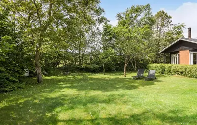 two chairs in a yard with trees and a house at 3 Bedroom Pet Friendly Home In Højslev in Højslev