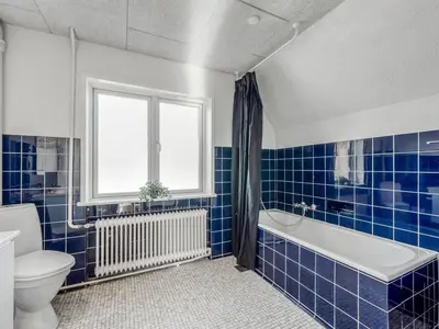 a blue tiled bathroom with a tub and a toilet at Holiday Home Ullakarin - 200m from the sea by Interhome in Thyborøn