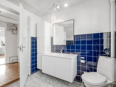 a bathroom with a white toilet and blue tiles at Holiday Home Ullakarin - 200m from the sea by Interhome in Thyborøn