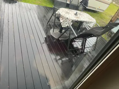 a table and chairs on a deck in the rain at Nice small house 5 minutes to the sea in Ranum