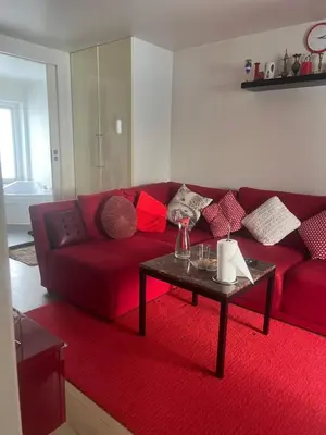 a living room with a red couch and a table at Nice small house 5 minutes to the sea in Ranum