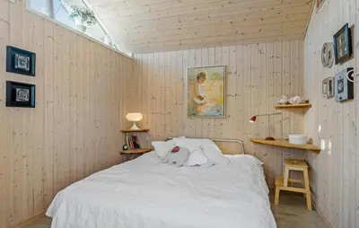 a bedroom with a white bed in a wooden wall at 4 Bedroom Beautiful Home In Pandrup in Pandrup