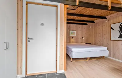 a bedroom with a bed in a room with wooden walls at Amazing Home In Roslev With Sauna in Roslev