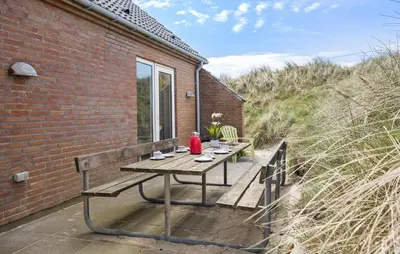 a picnic table on a patio next to a brick building at Cozy Home In Frøstrup With Sauna in Frøstrup