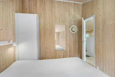 a bedroom with a white bed and wooden walls at Little Fiskerbanke - Lovely, Private, And Family-Friendly Holiday Home in Saltum