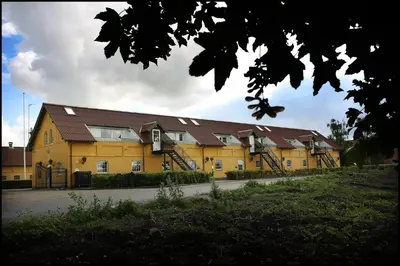 a large yellow building with two sets of stairs at Volstrup Ferieboliger in Stenild