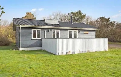 a small house with a white fence in a yard at 3 Bedroom Awesome Home In Vestervig in Vestervig