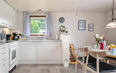 a kitchen with white cabinets and a table and a dining room at 3 Bedroom Stunning Home In Hurup Thy in Doverodde