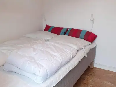 a white bed with a red and green pillow on it at 5 person holiday home in Vesløs-By Traum in Øsløs