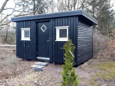 a black shed with two windows and a christmas tree at 5 person holiday home in Vesløs-By Traum in Øsløs