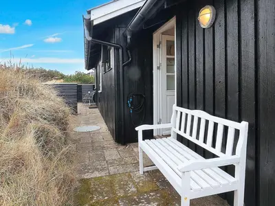 a white bench sitting outside of a black house at 5 person holiday home in Brovst-By Traum in Brovst