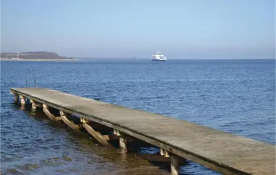 a pier in the ocean with a boat in the water at Holiday Home Farsø Op-1966 in Farsø