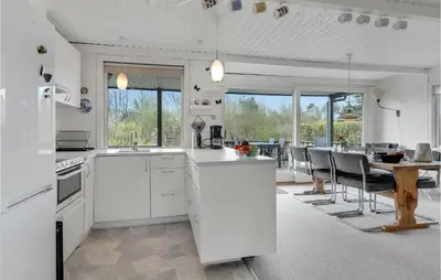 a kitchen with white appliances and a table with chairs at Holiday Home Farsø Qr-1965 in Farsø