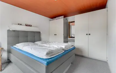 a bedroom with a large bed with white walls at Holiday Home Farsø Qr-1965 in Farsø