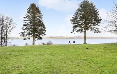 two trees and a bench on a hill near the water at Awesome Home In Roslev With Kitchen in Roslev