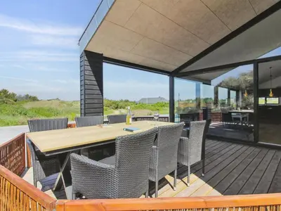 an outdoor deck with a wooden table and chairs at Holiday Home Kristiina - 500m from the sea by Interhome in Saltum