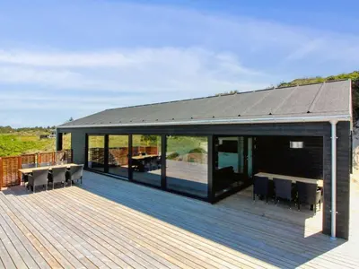 a large deck with glass doors and tables on it at Holiday Home Kristiina - 500m from the sea by Interhome in Saltum