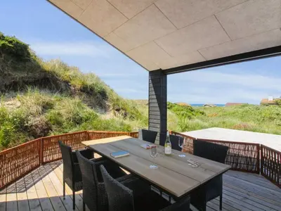 a dining table on a deck with a view of the ocean at Holiday Home Kristiina - 500m from the sea by Interhome in Saltum