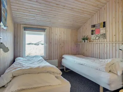 two beds in a wooden room with a window at Holiday Home Emelia - 50m from the sea by Interhome in Torsted