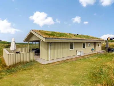 a house with a grass roof with a deck at Holiday Home Pinja - 400m from the sea by Interhome in Løkken