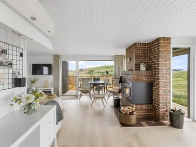 a living room with a brick fireplace and a table at Holiday Home Pinja - 400m from the sea by Interhome in Løkken