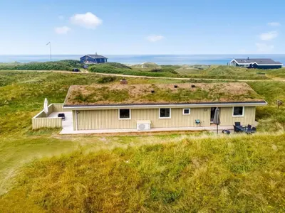 a house with a grass roof on top of a field at Holiday Home Pinja - 400m from the sea by Interhome in Løkken