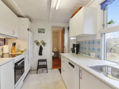 a kitchen with white cabinets and a sink and a window at Holiday Home Florencia - 450m from the sea by Interhome in Løkken