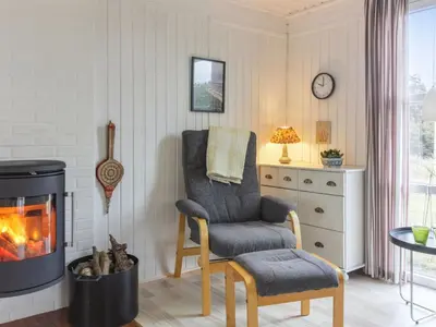 a living room with a chair and a fireplace at Holiday Home Florencia - 450m from the sea by Interhome in Løkken