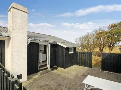 a house with a black fence and a patio at Holiday Home Florencia - 450m from the sea by Interhome in Løkken