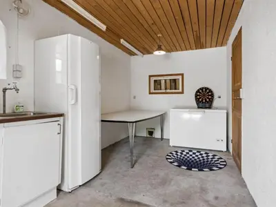 a kitchen with a table and a refrigerator at Holiday Home Månviva - 150m to the fjord by Interhome in Redsted
