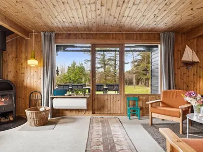 a living room with wooden walls and a large window at Holiday Home Jukka - 2km from the sea by Interhome in Snedsted