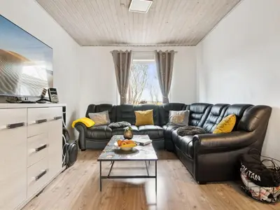 a living room with a leather couch and a table at Holiday Home Elara - 300m from the sea by Interhome in Thyholm