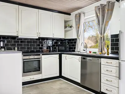 a kitchen with white cabinets and stainless steel appliances at Holiday Home Elara - 300m from the sea by Interhome in Thyholm