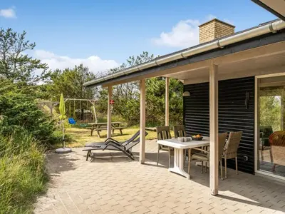 a patio with a table and chairs and a playground at Holiday Home Selenia - 1km from the sea by Interhome in Saltum